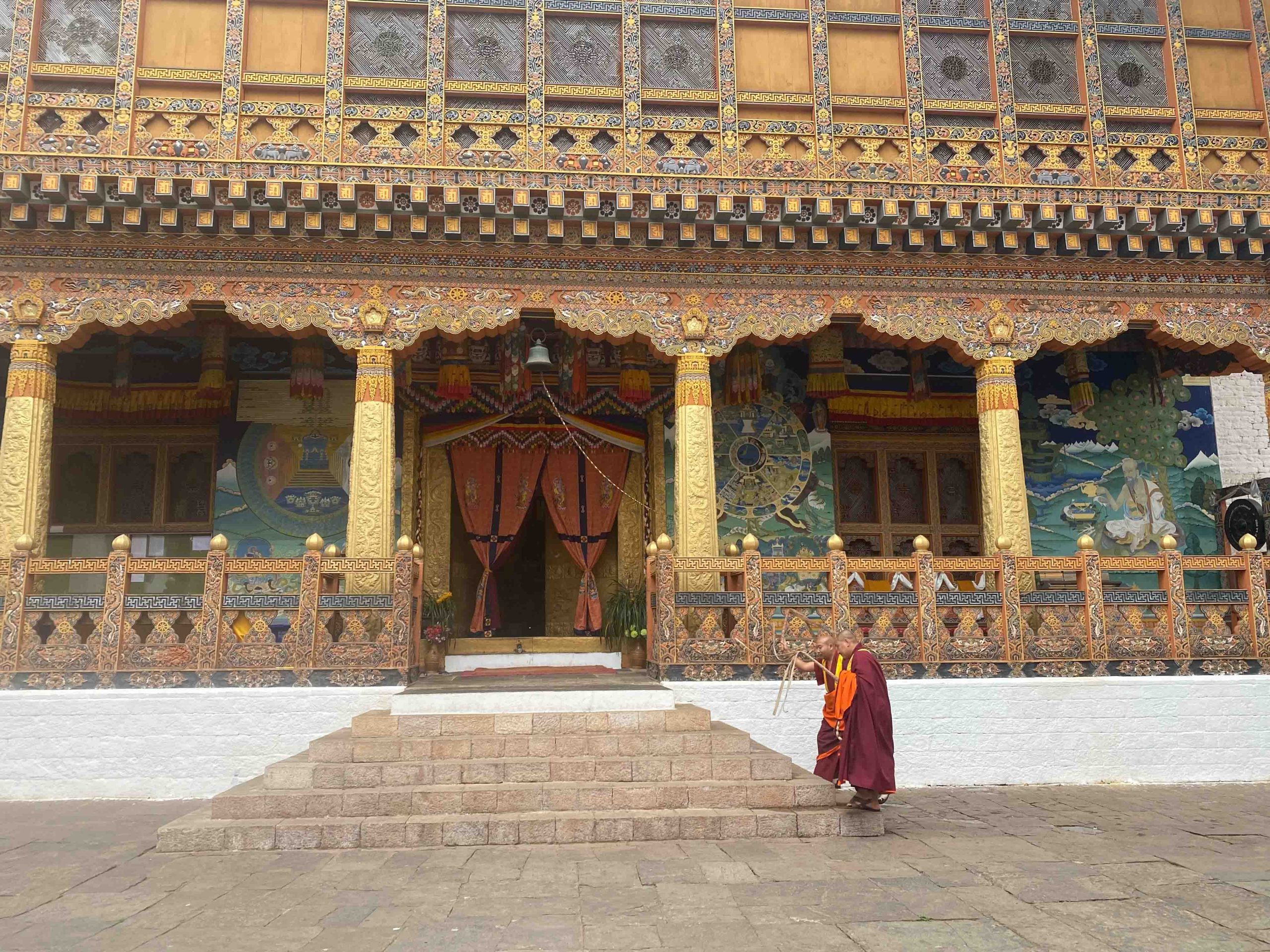 Two monks crossing the courtyard of a painted dzong